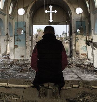 Un cristiano prega in una chiesa distrutta ad Aleppo